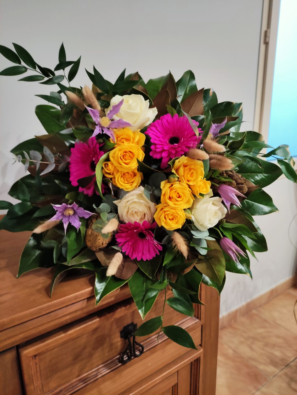 bouquet de fleurs ton jaune et fuschia sur une structure en feuilles de magnolia